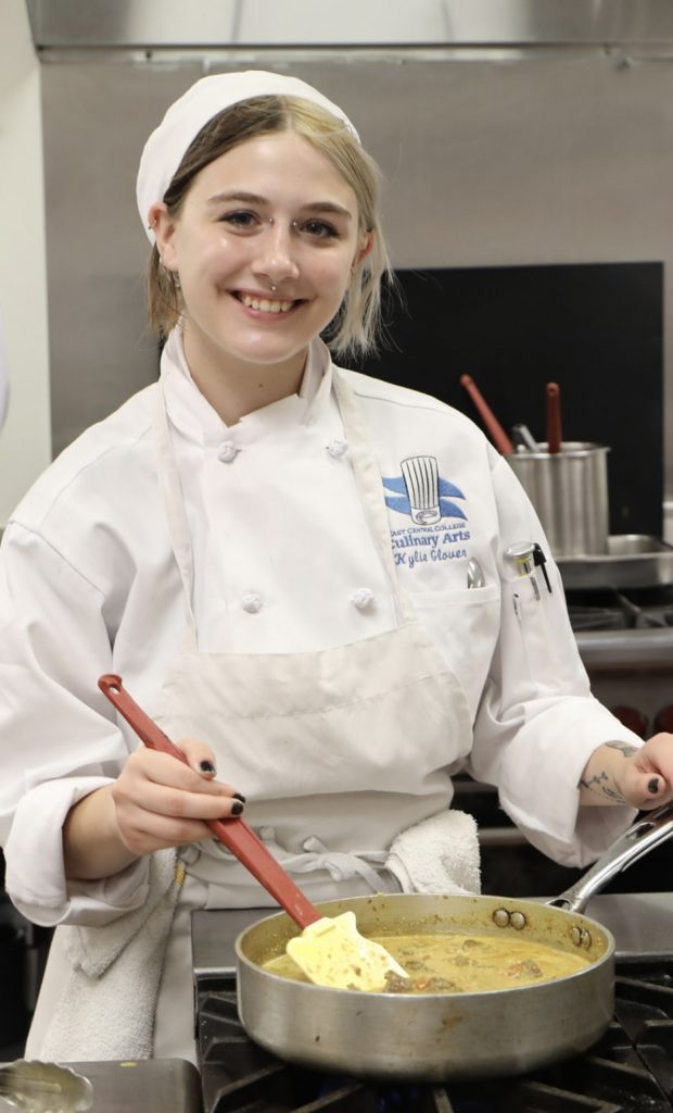 Culinary arts student smiling and stirring food in pan