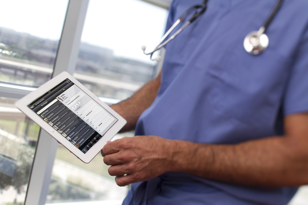 Nurse in blue scrubs checking patient data on tablet