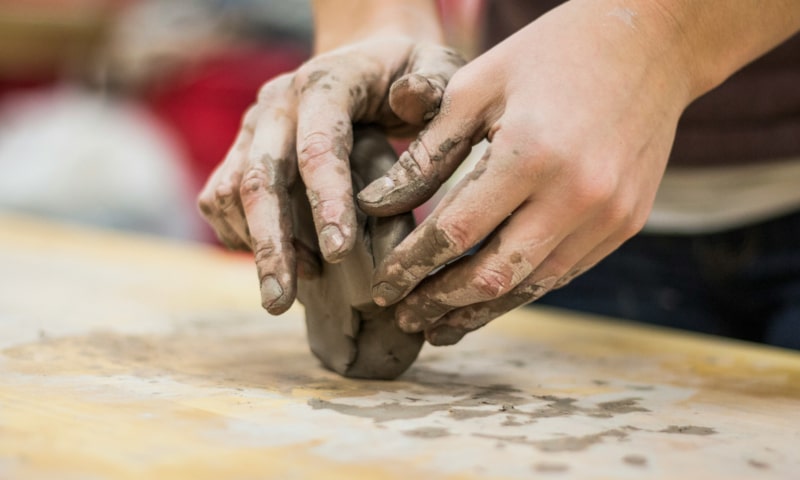 Hands manipulating ball of clay