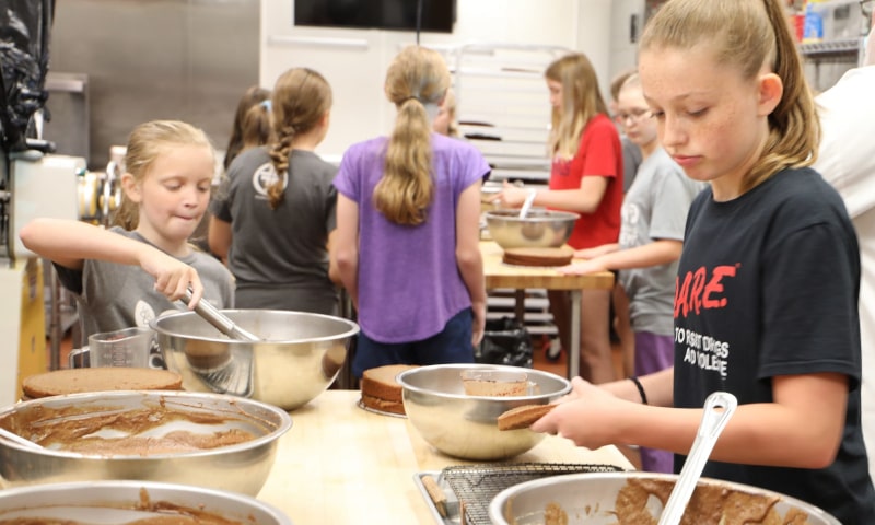 Young students mixing pie dough in kitchen