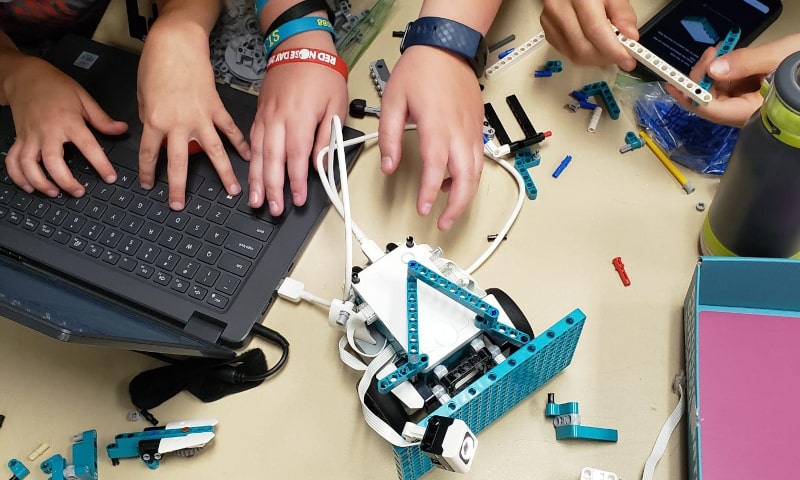 Overhead shot of hands working with laptop and Lego robotics