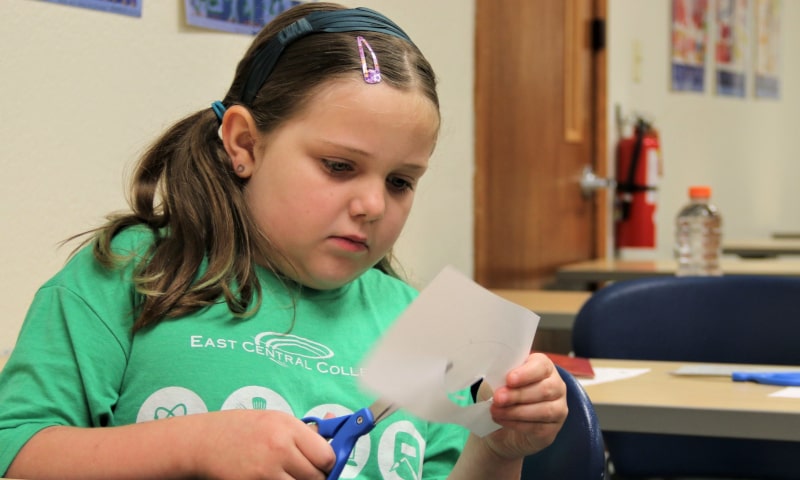 Girl cutting paper with scissors