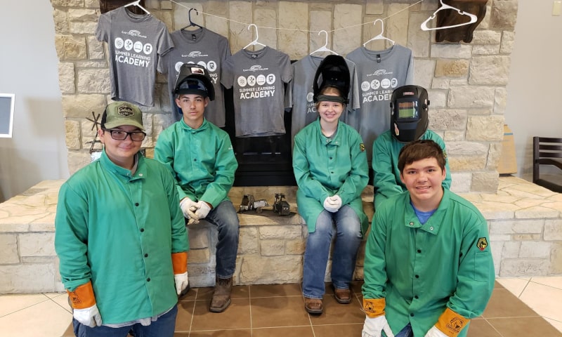 Young students posing in welding gear
