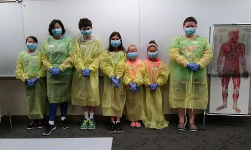 Line up of students in surgical gear posing for photo
