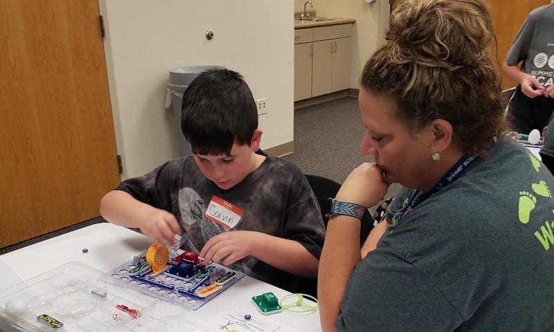 Teacher overseeing student work with science kit