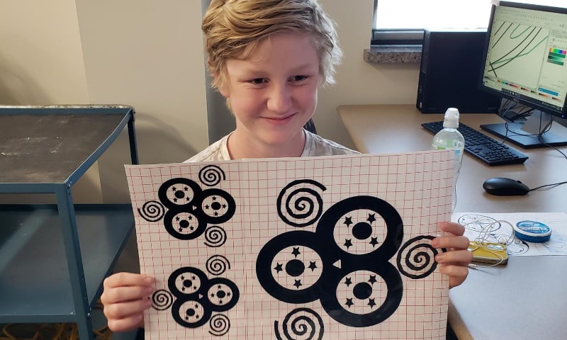 Young student holding a paper with designs