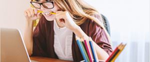 Student biting pencil while looking at laptop computer screen