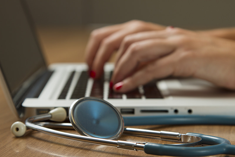 A stethoscope, laptop, smartphone, and medical professional