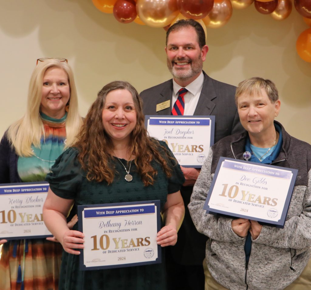 Four ECC employees holding certificates for 10 years of service, 
