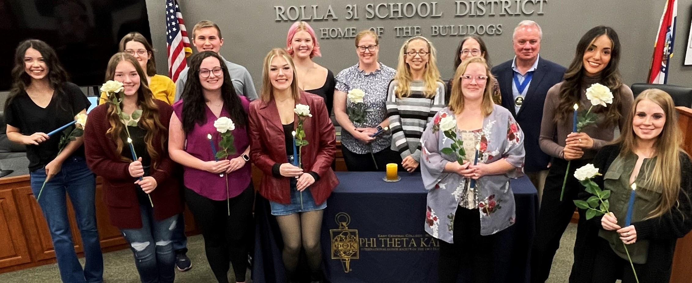 Group of Phi Theta Kappa inductees holding candles and roses during an induction ceremony at Rolla 31 School District, part of East Central College's Rolla campus events.