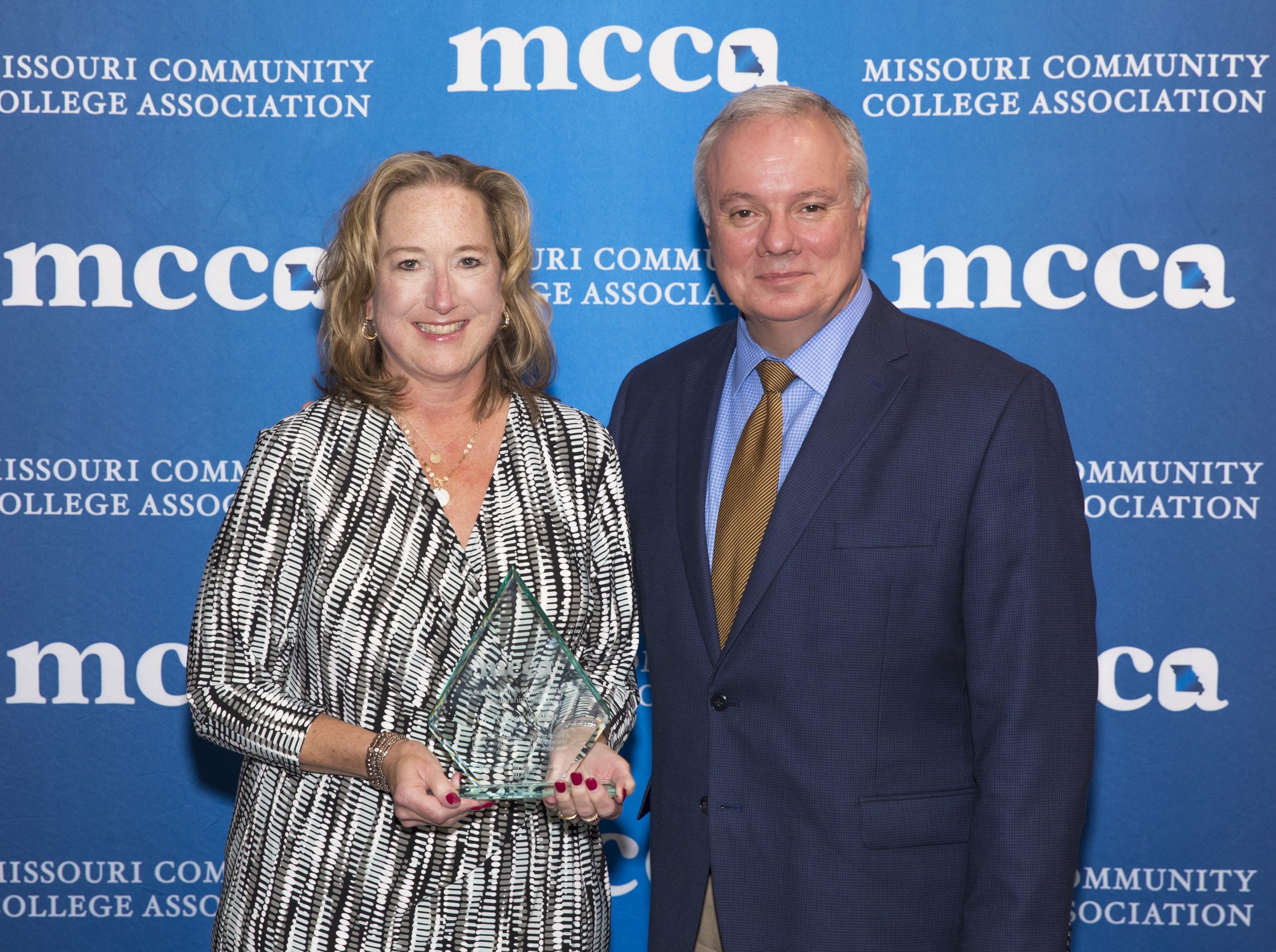Dr. Robyn Walter, Vice President for Academic Affairs and Chief Academic Officer at East Central College, holding the 2024 MCCA Administrative/Professional Award, standing alongside ECC President Dr. Jon Bauer at the MCCA 60th Convention and Trade Show in Branson, with an "MCCA" backdrop behind them.