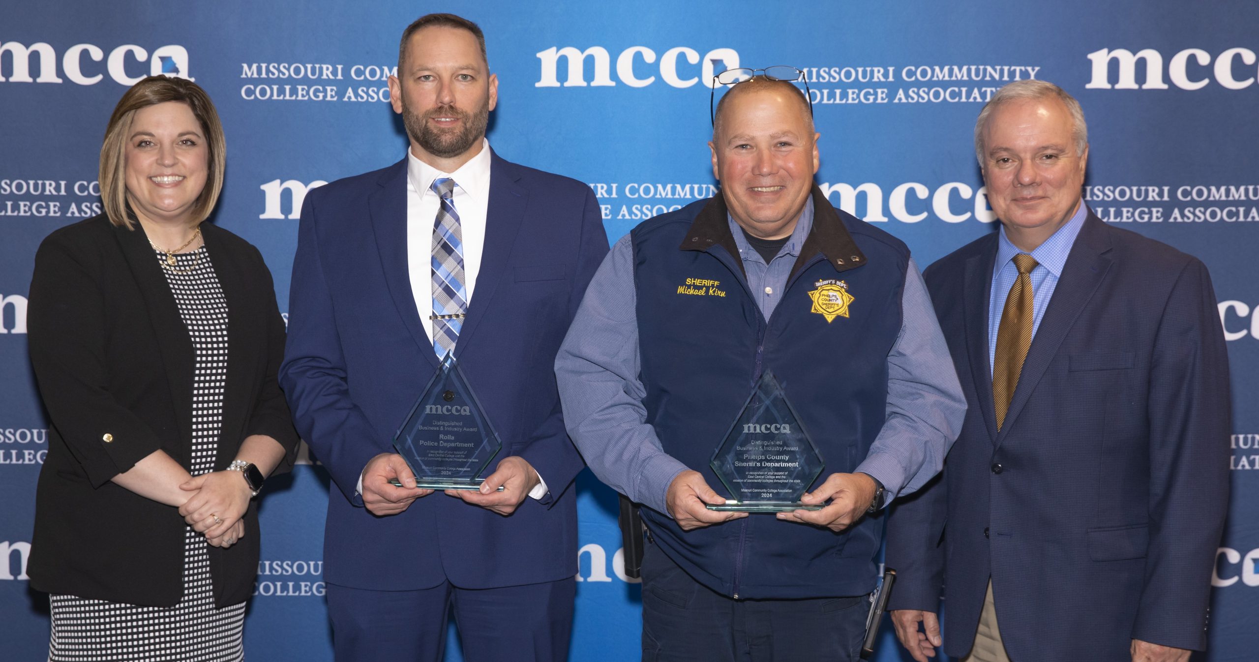 A group photo featuring ECC Rolla Director Christina Ayres, Rolla Police Department Assistant Chief William Loughridge, Phelps County Sheriff Michael P. Kirn, and ECC President Dr. Jon Bauer, standing together with awards in hand. The awards recognize the Phelps County Sheriff’s Department and the Rolla Police Department for receiving the 2024 MCCA Business & Industry Award for their collaboration with East Central College in forming the Phelps Law Enforcement Training Center (LETC). An "MCCA" backdrop is visible behind them.